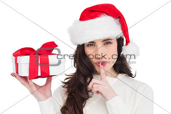 Festive brunette holding gift and keeping a secret