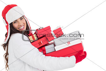 Festive brunette in winter clothes holding many gifts