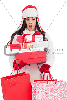 Surprised brunette in winter clothes holding many gifts and shopping bags