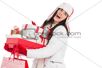 Brunette in winter clothes holding many gifts and shopping bags