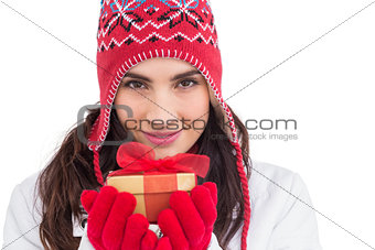 Smiling brunette in winter clothes holding gift