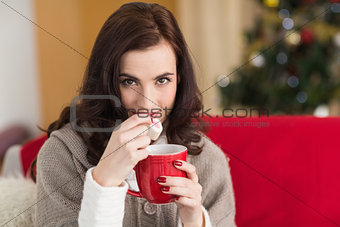 Brunette holding mug and eating marshmallow at christmas