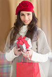 Smiling brunette holding gift and shopping bags