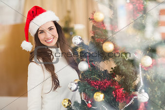 Smiling brunette decorating a christmas tree