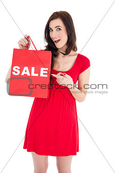 Stylish brunette in red dress showing sale bag