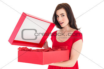 Surprised brunette in red dress opening gift