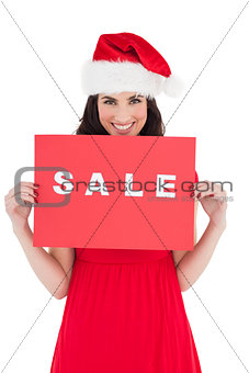 Festive brunette in red dress holding sale sign