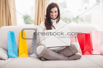 Brunette shopping online with laptop on the couch