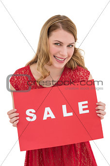 Smiling blonde showing a red sale poster