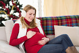 Pregnant woman rubbing her belly on the couch