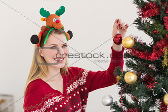 Woman hanging christmas decorations on tree