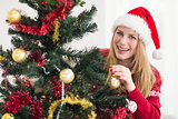 Smiling woman hanging christmas decorations on tree