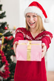 Smiling festive woman offering a pink gift