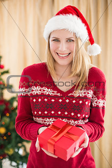 Festive pretty blonde woman offering gift