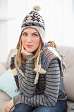 Cute blonde in winter hat sitting on couch posing