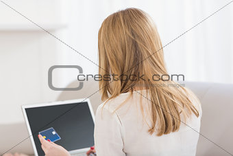 Rear view of a pretty blonde shopping online with laptop