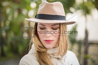 Pretty blonde woman with hat posing while looking down