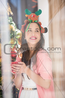 Smiling brunette in christmas hat holding mug