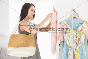 Smiling shopping brunette looking at shirt at clothes store