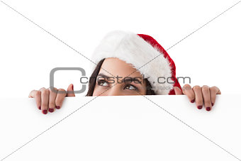 Pretty brunette in santa hat showing white poster