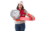Surprised brunette holding a clock and gift