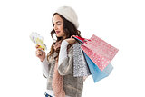 Happy brunette holding cash and shopping bags