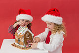 Festive little girls making a gingerbread house