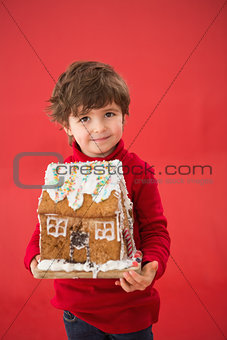 Festive little boy holding gingerbread house