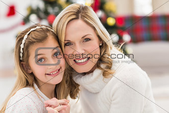 Festive mother and daughter beside christmas tree