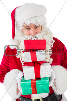 Smiling santa holding pile of gifts