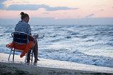 Woman sitting on chair by sea and using pad