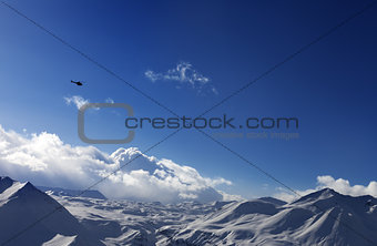 Helicopter above snowy plateau and sunny sky