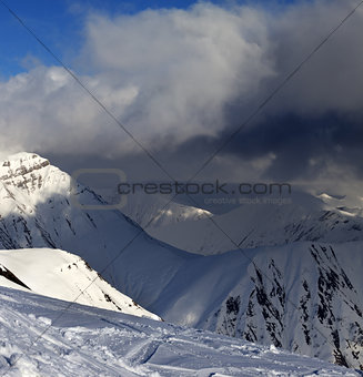 Off-piste slope and mountains with storm clouds