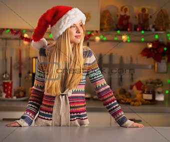 Portrait of young woman in christmas decorated kitchen looking o