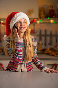 Happy teenager girl in santa hat talking cell phone in christmas
