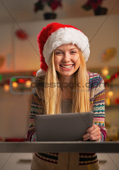 Portrait of happy teenager girl in santa hat using tablet pc