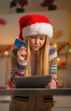 Portrait of thoughtful teenager girl in santa hat with credit ca