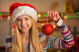 Portrait of smiling teenager girl in santa hat showing christmas