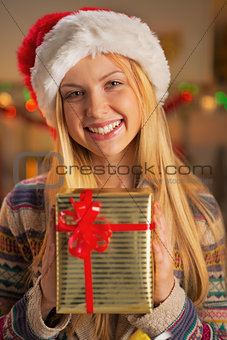Portrait of smiling teenager girl in santa hat holding christmas