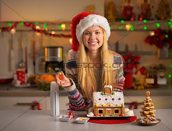Portrait of smiling teenager girl in santa hat decorating christ