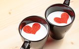two cup of milk with decorative hearts on wood table, concept of valentine day