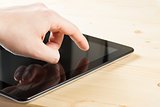 male hand is touching digital tablet pc on wood table