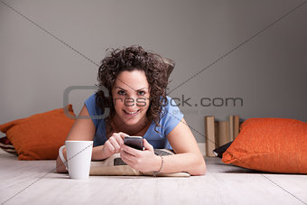 girl enjoying her mobile while drinking from a mug