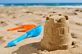 sandcastle and toy shovels on the sand of a beach