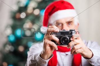 Senior man taking photo on Christmas background