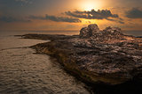 Sunset over the Sea and Rocky Coast with Ancient Ruins