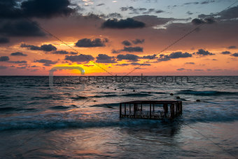 Tropical Beach with Empty Cage in the Sea at Sunset