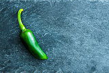 Closeup on green chili pepper on stone substrate