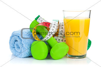 Two green dumbells, tape measure and orange juice. Fitness and h