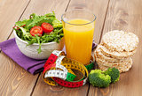 Healthy food and tape measure over wooden table